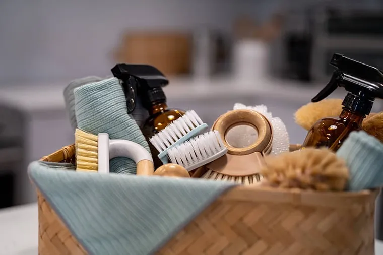 Cleaning supplies laid out in a woven basket.