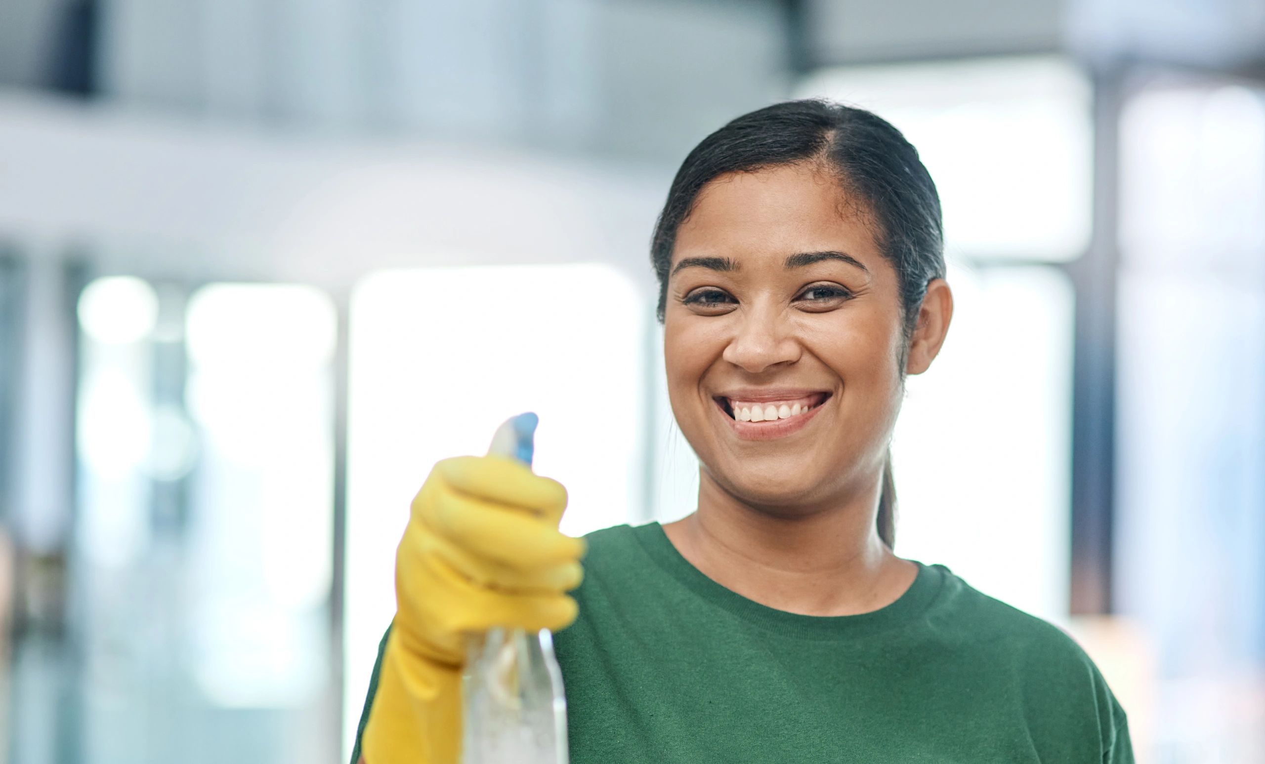 Portrait of a young woman cleaning a modern surface.